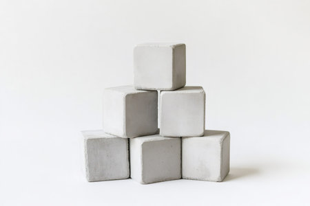 Minimalist artwork featuring concrete cubes arranged in a pyramid shape against a clean white backdropの素材