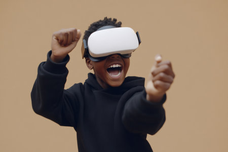 Young boy having fun playing a videogame using a virtual reality headset, isolated on beige backgroundの素材