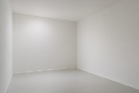 Empty white room with gray floor illuminated by a ceiling light, perfect for showcasing interior design projectsの素材