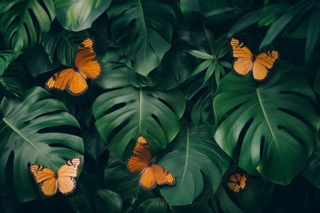 Orange monarch butterflies amidst vibrant green foliage, conveying peace and natural beautyの素材