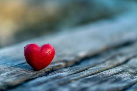 Minimalist vibrant red heart symbol placed on a weathered wooden texture, representing the concept of love and romanceの素材