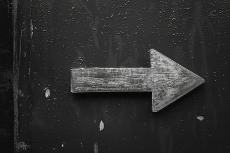 Grayscale photo of a rustic arrow sign, symbolizing direction or guidance on a grunge surfaceの素材