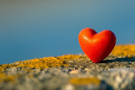 Vibrant red heart-shaped symbol stands out against a blurred natural backdrop, conveying love and simplicityの素材