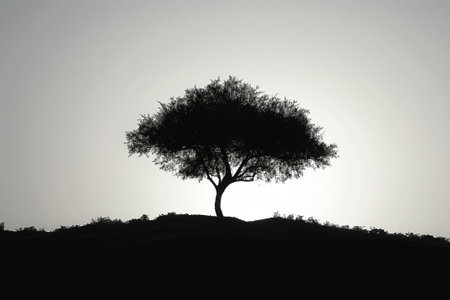 Minimalist silhouette of a lone tree against a soft twilight sky, symbolizing tranquility and nature's graceの素材