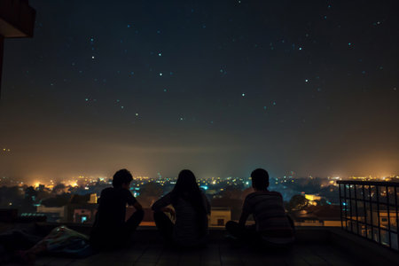 Silhouettes of an Indian family enjoying a stargazing session from their urban rooftopの素材