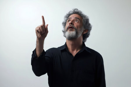 Bearded mature man pointing his finger up with an amazed expression on a white backgroundの素材