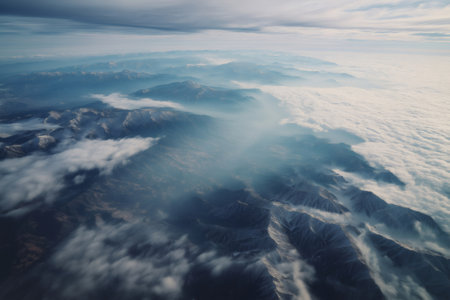 Breathtaking aerial view of clouds gently flowing over a majestic snow capped mountain range, creating a stunning display of nature's beautyの素材