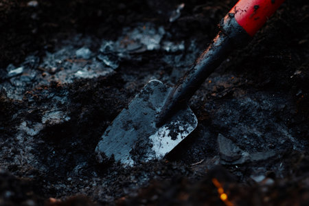 Small gardening trowel digging into rich, dark soil, preparing the earth for planting vibrant flowers or fresh vegetablesの素材