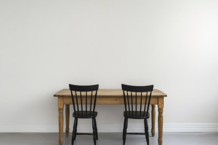 Minimalist dining room interior with wooden table and two black chairs standing in front of a white wallの素材