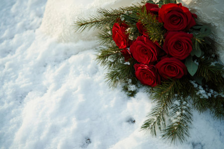 Beautiful red roses bouquet and white wedding dress lying on the snow during a winter wedding ceremonyの素材