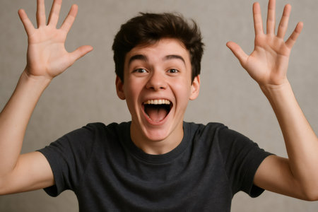 Portrait of a joyful teenager with open mouth and raised hands, expressing excitement and happinessの素材