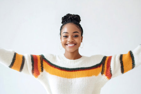 Happy young African American woman with a bright smile, stretching out her arms against a white background, symbolizing openness and happinessの素材