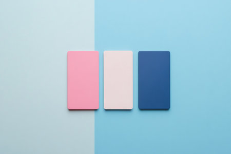 Blank pink, beige, and blue cards presenting a simple color combination on a two tone blue backgroundの素材