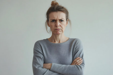 Mature woman deeply frowning, furrowing brows, and pursing lips, conveying strong negative emotions, frustration, or disagreementの素材