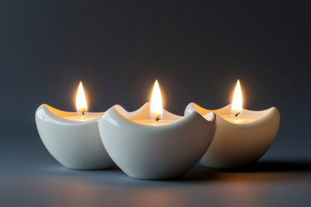 White candles with glowing flames creating a peaceful, warm atmosphere against a dark background, representing tranquilityの素材