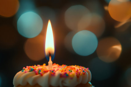 Close up of a lit birthday candle on a cupcake, featuring colorful sprinkles and a soft bokeh backgroundの素材