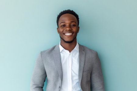 Young professional black man looking at camera with a confident smile, wearing a blazer over a white shirtの素材