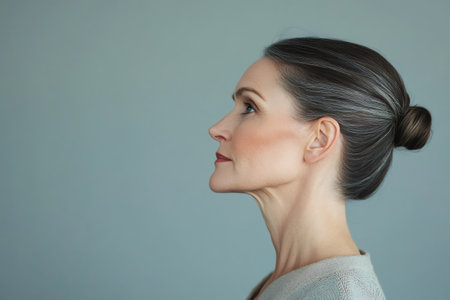 Mature woman looking up with a thoughtful expression, showing natural beauty and aging gracefully in profileの素材