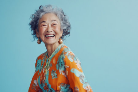 Joyful Asian grandmother smiling broadly, celebrating life and happiness with emotion on a genuine plain backgroundの素材