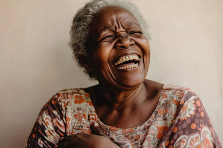 Senior African American woman laughing heartily with closed eyes and wide mouth, expressing genuine happiness and positive emotionの素材