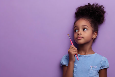 Young African American girl holding a pink brush, looking up with a thoughtful, curious expression against a purple backgroundの素材