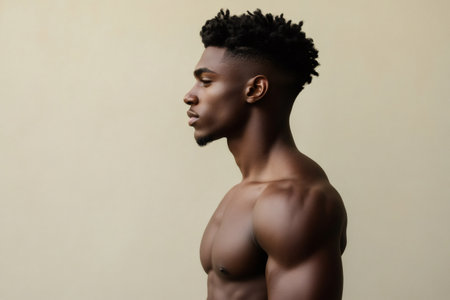 Attractive young black man standing in profile, illustrating modern hairstyle and athletic physique with confidenceの素材