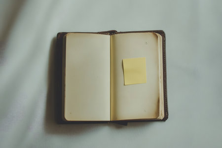 Open journal with blank pages, a simple aged yellow sticky note providing reminder or idea. Copy space for textの素材