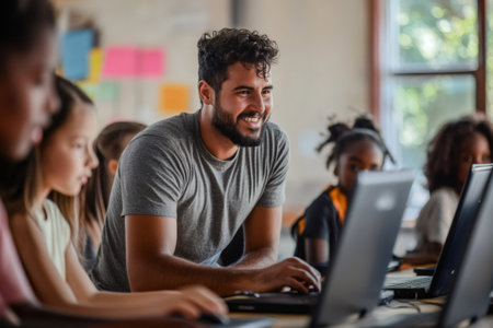 Smiling volunteer instructor guiding diverse group of elementary school children learning digital skills on laptops in a classroomの素材