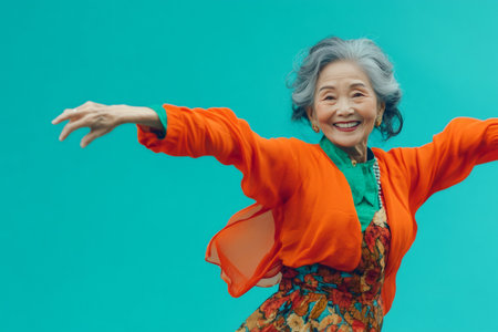 Senior East Asian woman with gray hair smiling and dancing actively. She expresses happiness and a vibrant, healthy lifestyleの素材
