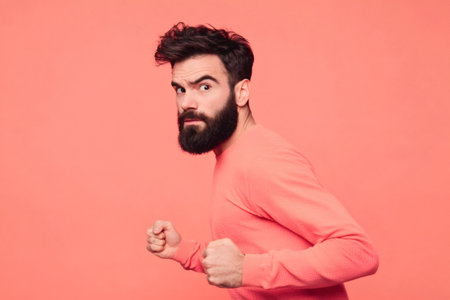 Bearded man running in place or preparing to run, looking back at camera with a focused and startled expression, fists clenchedの素材