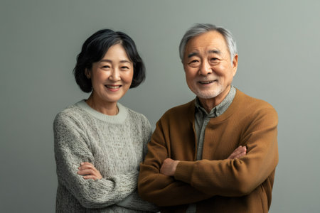 Senior Asian man and woman standing together, smiling happily with crossed arms. Reflecting confidence and well beingの素材