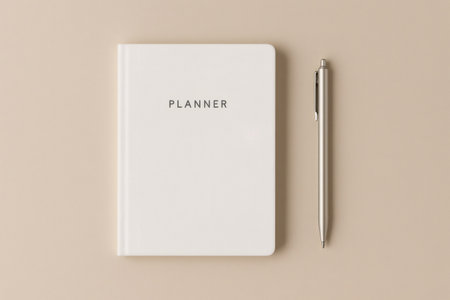 Simple planner and pen displaying productivity, planning, and scheduling tools on a neutral beige background in a flat layの素材