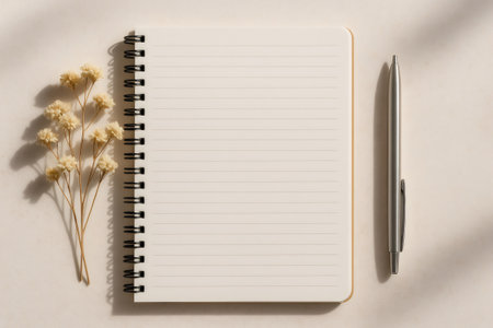 Notebook showing blank lined page with pen and dried flower branch on a neutral background, creating a cozy and aesthetic compositionの素材
