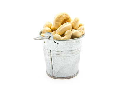 cashew nuts in a wooden bowl isolated on whiteの写真素材