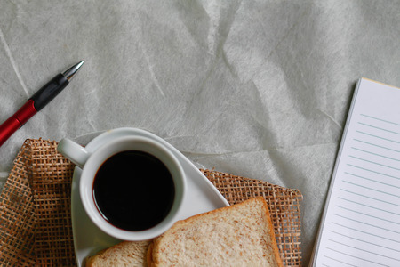 cup of black coffee and Whole wheat bread with a notesの写真素材