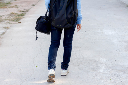Young woman with backpack walking along the roadの写真素材