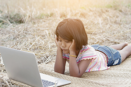 A girl playing laptop in the field.の写真素材