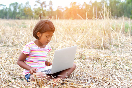 A girl playing laptop in the field.の写真素材