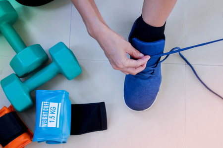 woman tying shoelaces in gym with fitness equipment