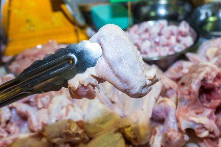 Pliers are cubed raw chicken wings, shoot in the marketの写真素材