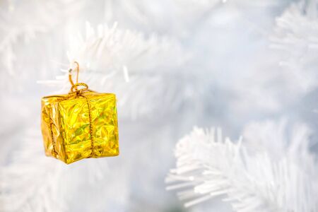 little golden gift box hang on white christmas treeの写真素材