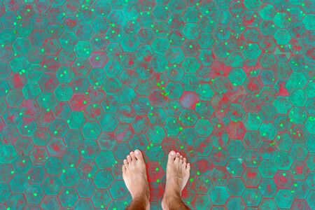 Men's feet on hexagonal tile floor and yellow flower petals