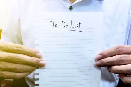 man in white shirt hold paper to do listの写真素材