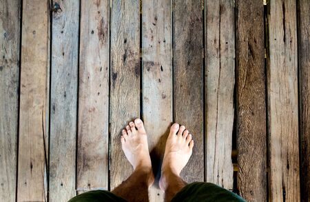 Man's feet stand on old plank woodの写真素材