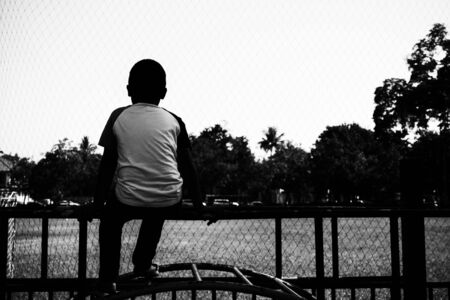 lonely boy sitting alone at the playgroundの写真素材