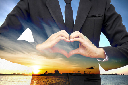 Double exposure sunset at harbor and businessman make heart-shaped. concept love to transportation.の写真素材
