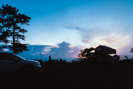 People are camping at the top of the hill at sunsetの写真素材