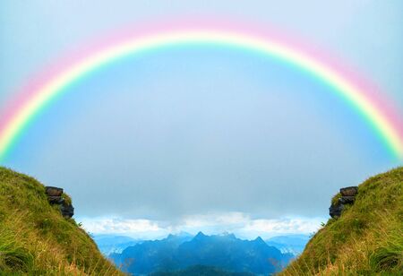 Two mountain peaks with a rainbow in the middleの写真素材
