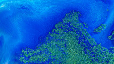 A light and dark blue gradient ink pattern mixed with gold glitter.の写真素材