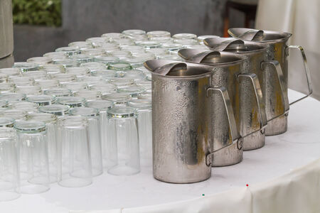 Inverted glass and stainless steel jug of cold water on the table.の写真素材
